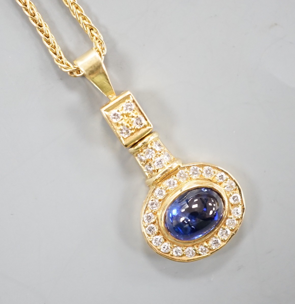A modern yellow metal, cabochon sapphire and diamond set cluster pendant, overall 30mm, gross 4 grams, on a modern 9ct gold chain, 46cm, 4,3grams.